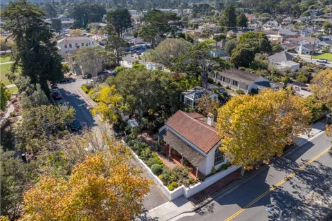 a view of a house with a small yard and large tree