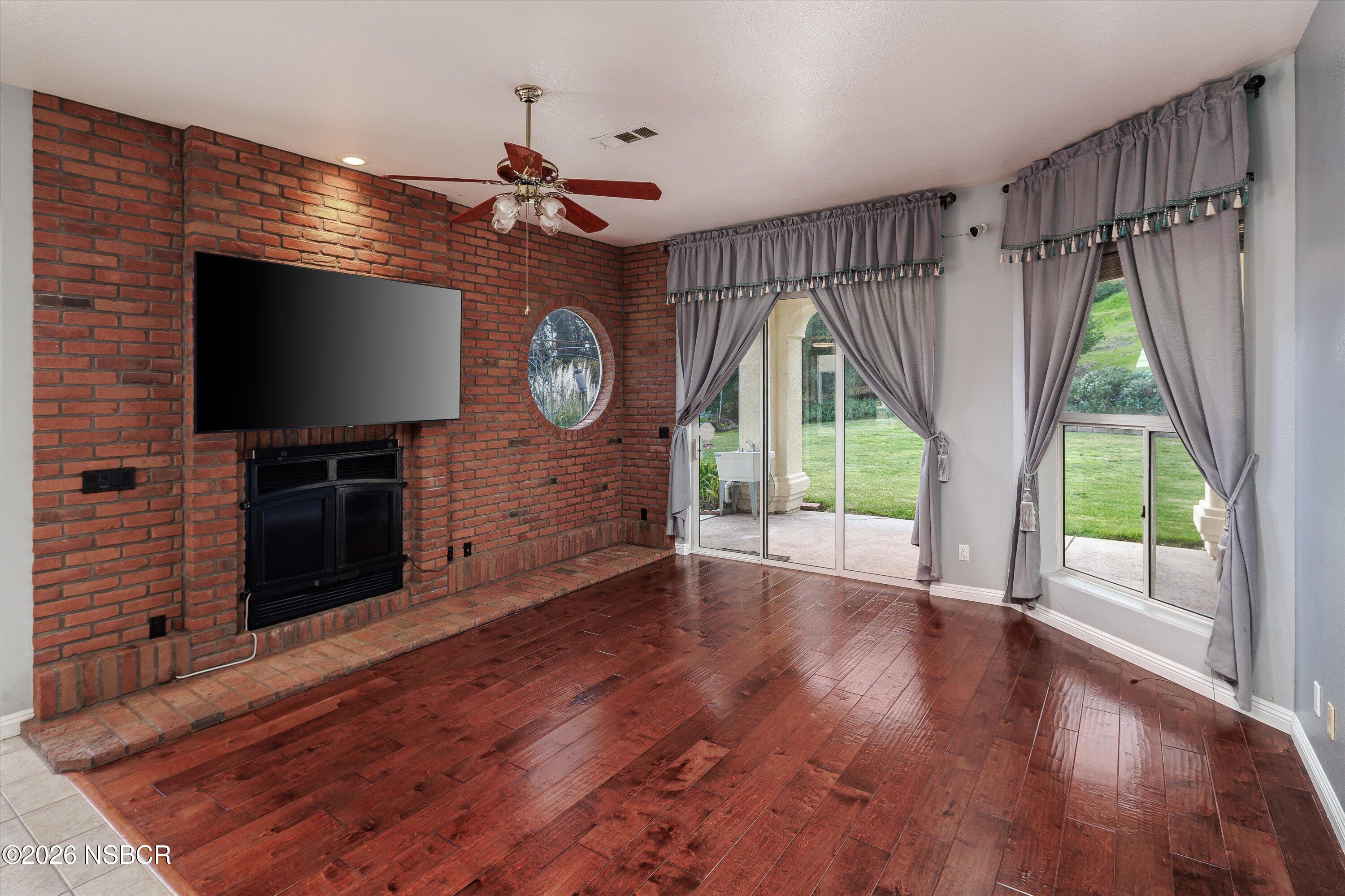 2655 Adobe Falls Road Lompoc, CA 93436 - Photo 18 of 51 a view of a livingroom with wooden floor a ceiling fan and a fireplace