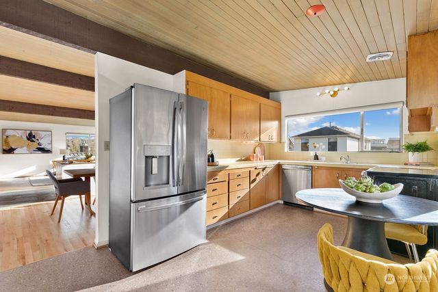 a kitchen with stainless steel appliances granite countertop a refrigerator a stove and a sink with dishwasher