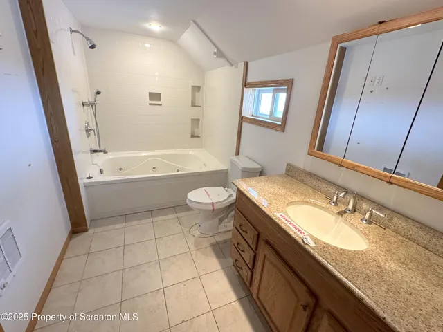 a bathroom with a granite countertop sink a toilet a mirror a bathtub and shower