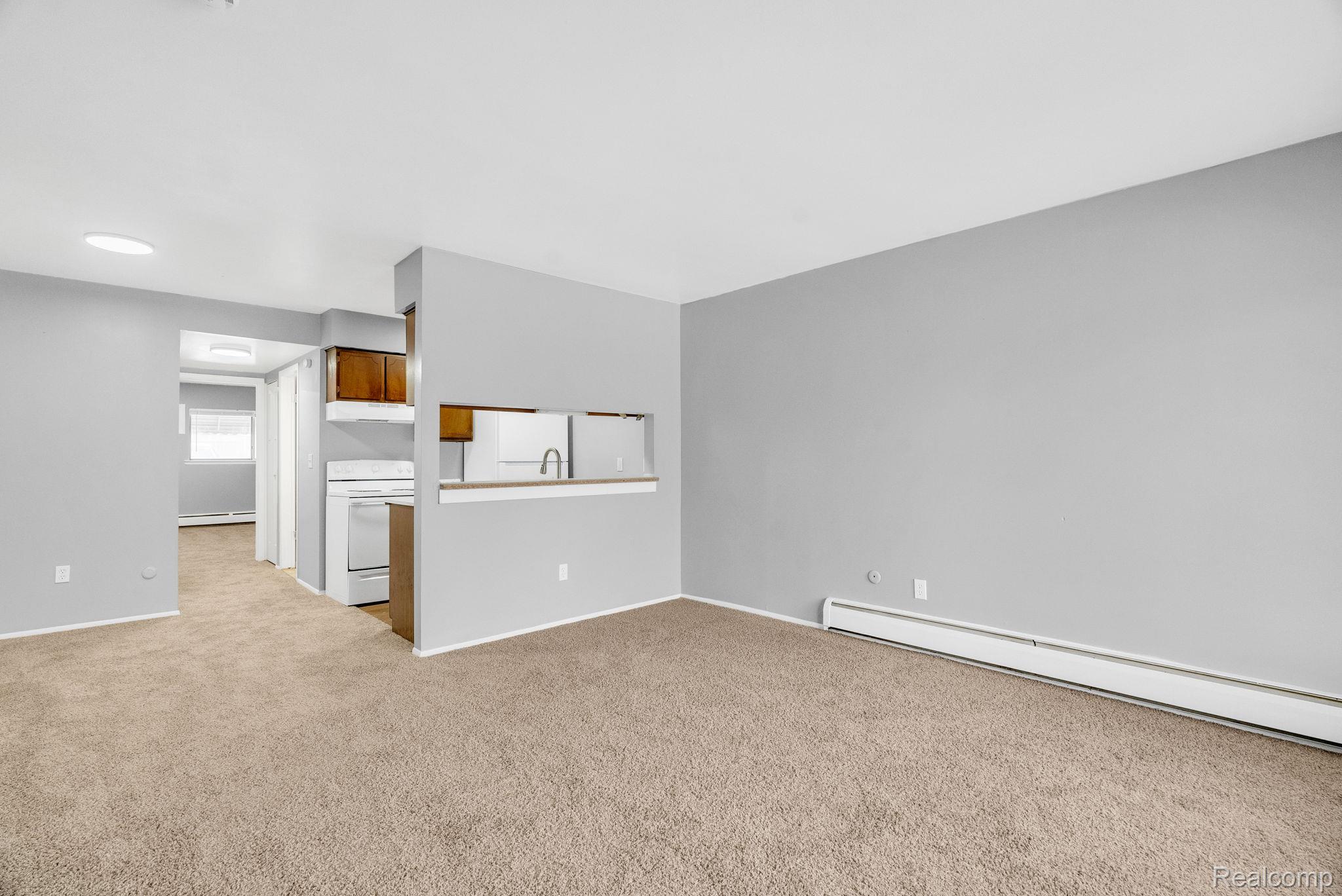 4535 Cadieux Road, Unit 42 / 210 Detroit, MI 48224 - Photo 4 of 16 Unfurnished living room featuring carpet flooring and a baseboard radiator