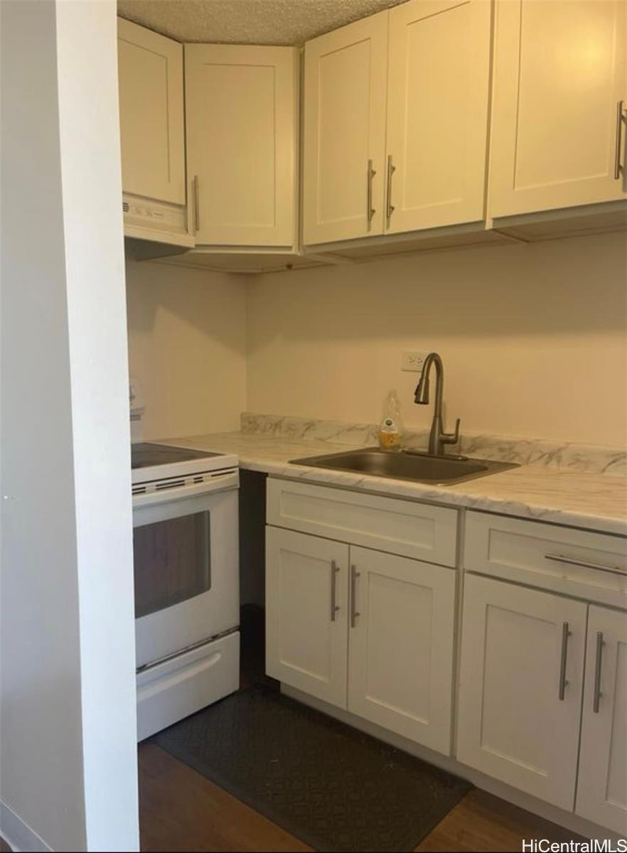 1560 Thurston Avenue, Unit 502 Honolulu, HI 96822 - Photo 4 of 9 a kitchen with granite countertop white cabinets and a sink