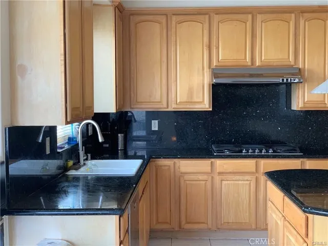 a kitchen with granite countertop a sink a stove and cabinets