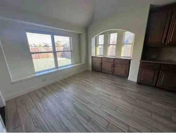 an empty room with wooden floor and windows