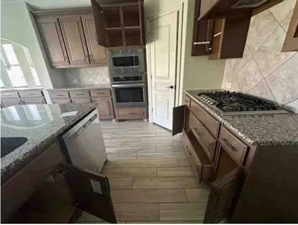 a kitchen with granite countertop a sink stove and refrigerator
