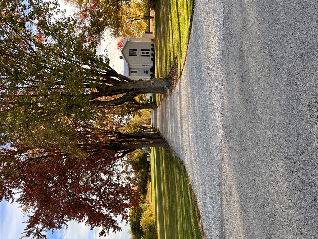 2086 Scheyhing Road Lewisburg, OH 45338 - Photo 28 of 29 An inviting gravel driveway leads to a classic home, framed by lush trees displaying autumnal colors.
