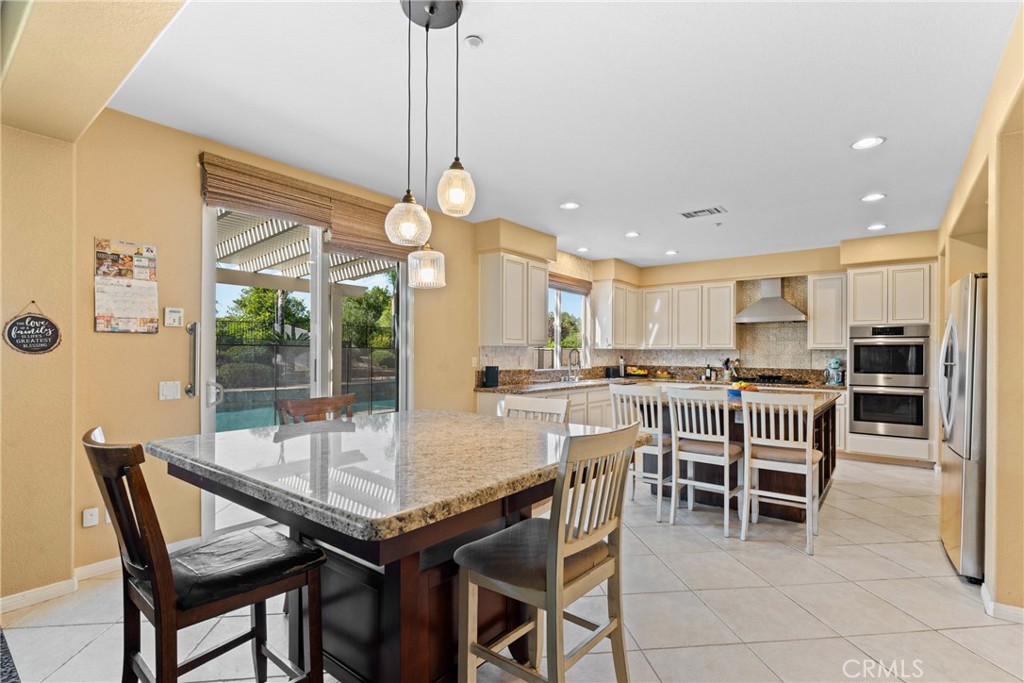 1137 Pamplona Drive Riverside, CA 92508 - Photo 22 of 50 a dining area with a table chairs and a kitchen view