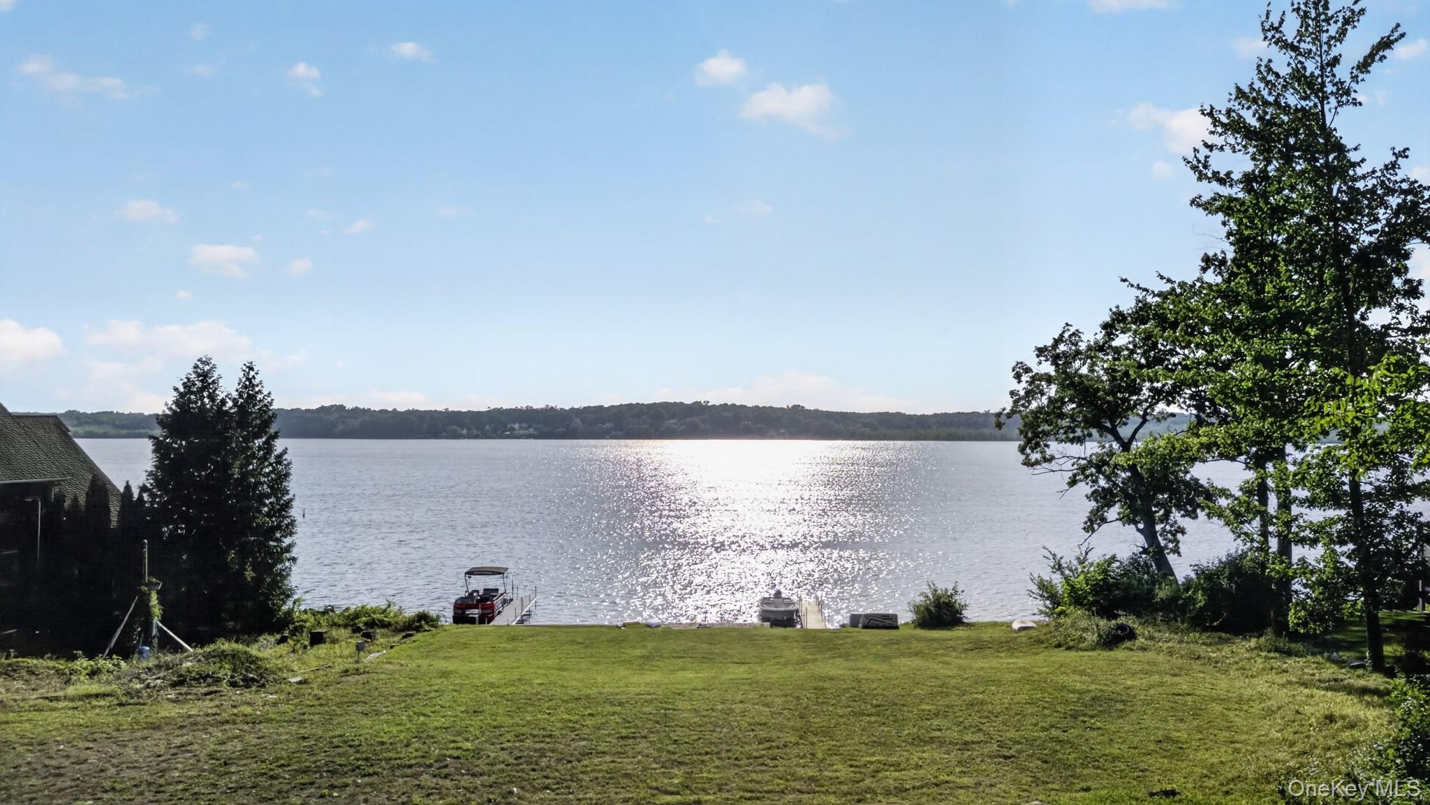 355 Lakeside Road Newburgh, NY 12550 - Photo 11 of 14 Expansive waterfront property featuring a wide lake frontage, a manicured lawn, established trees, and a private dock with a boat