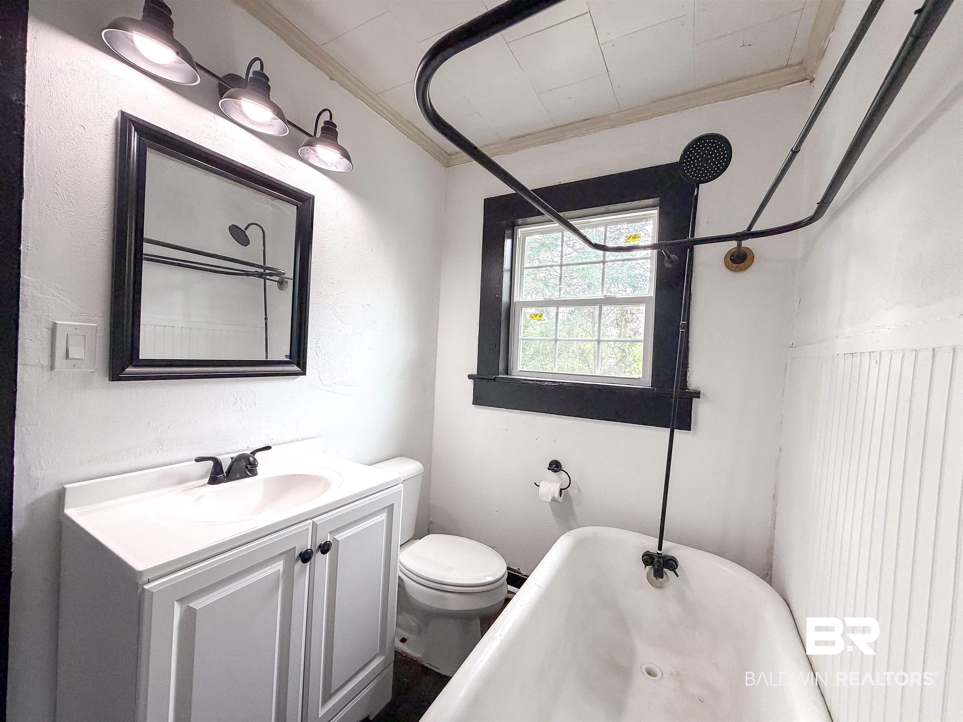 38 Flock Avenue Mobile, AL 36610 - Photo 18 of 27 Compact bathroom featuring a white vanity with integrated sink, black-framed mirror, and three-light vanity fixture
