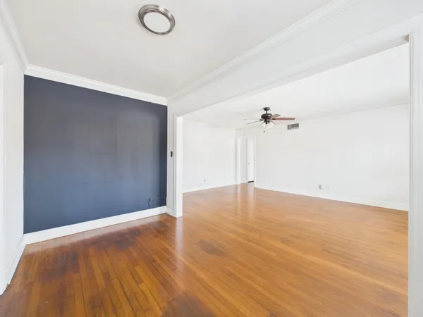 a view of empty room with wooden floor and fan