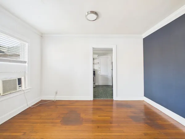 an empty room with wooden floor and fan