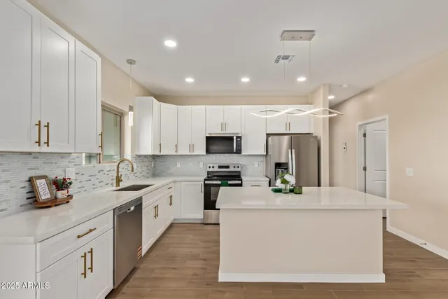 a kitchen with stainless steel appliances kitchen island granite countertop a stove a sink a refrigerator and white cabinets