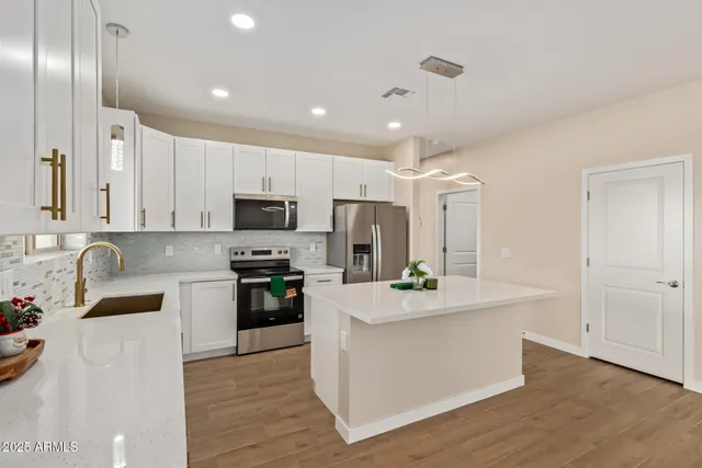 a large kitchen with stainless steel appliances granite countertop a lot of counter space and wooden floor