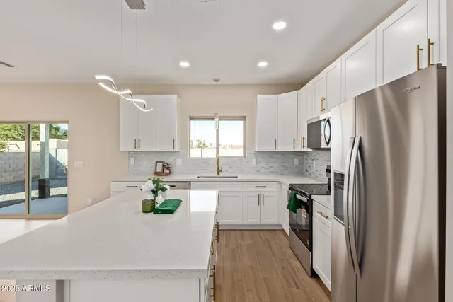 a kitchen with stainless steel appliances a refrigerator sink and white cabinets
