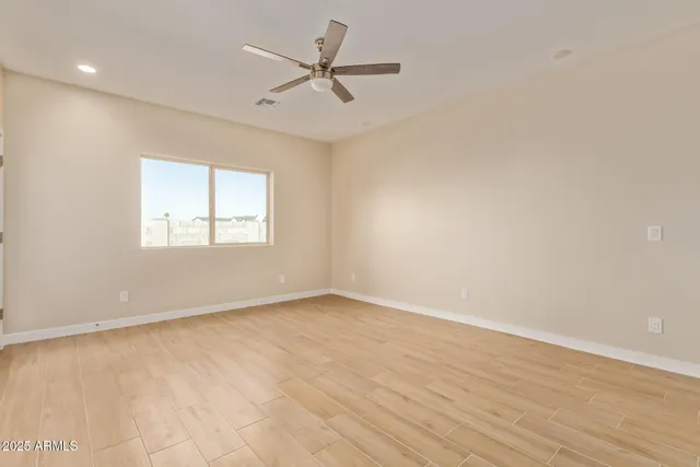 an empty room with wooden floor ceiling fan and window