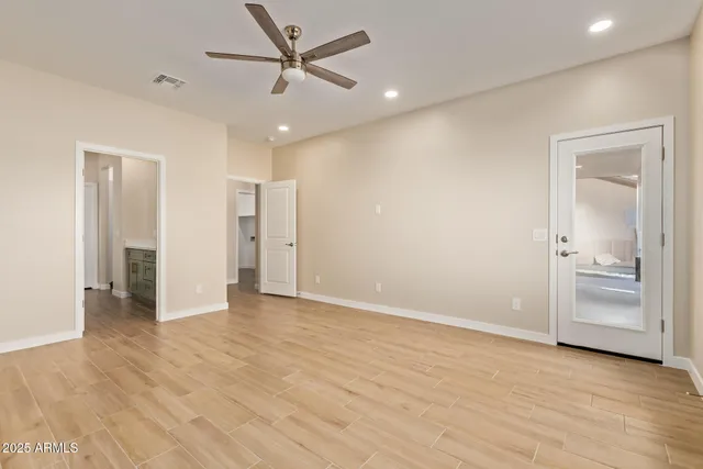 an empty room with wooden floor and ceiling fan