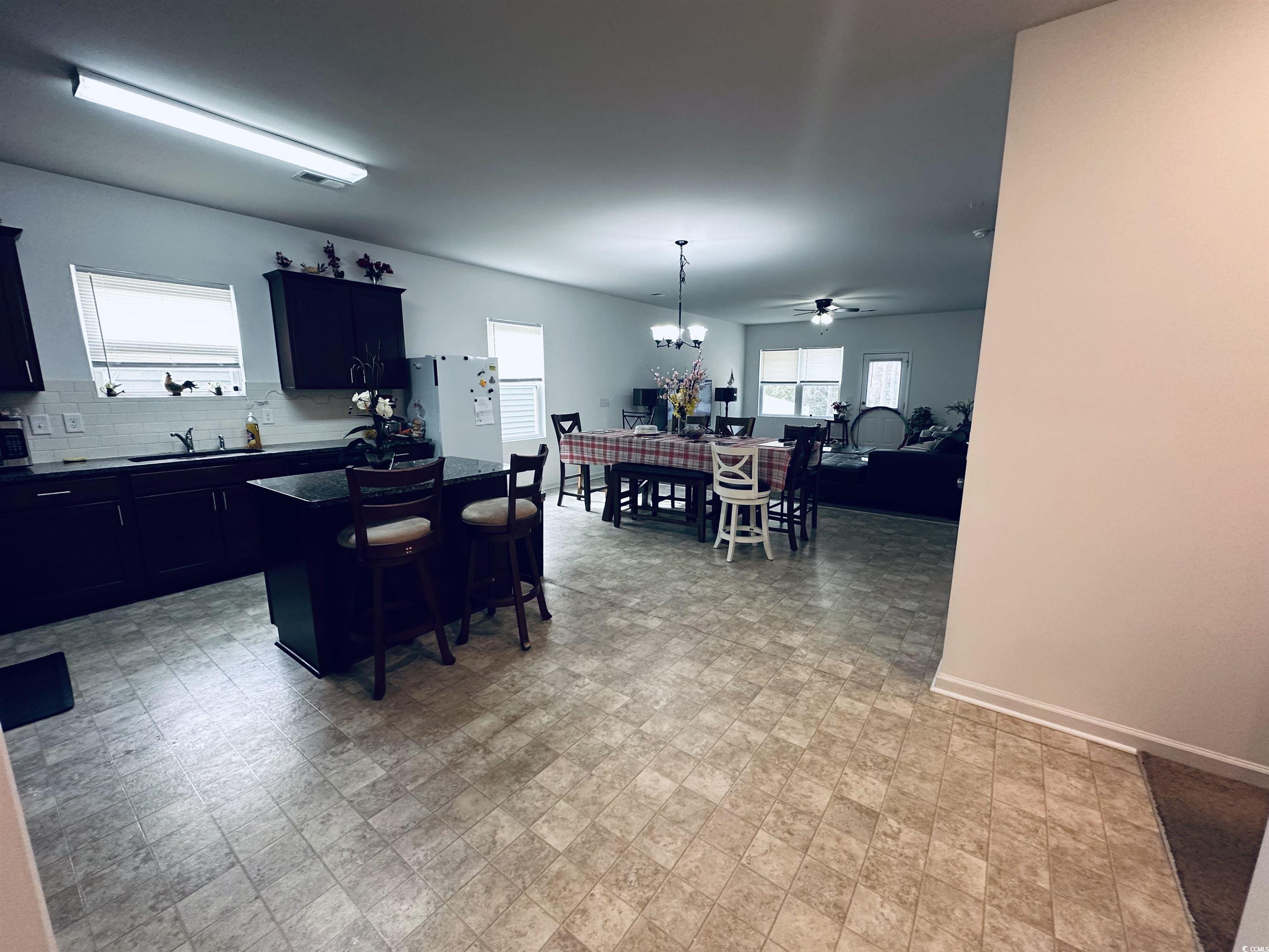 5260 Walnutwood Trail Myrtle Beach, SC 29579 - Photo 30 of 30 Kitchen featuring dark cabinets, decorative light fixtures, a kitchen bar, a kitchen island, and open floor plan