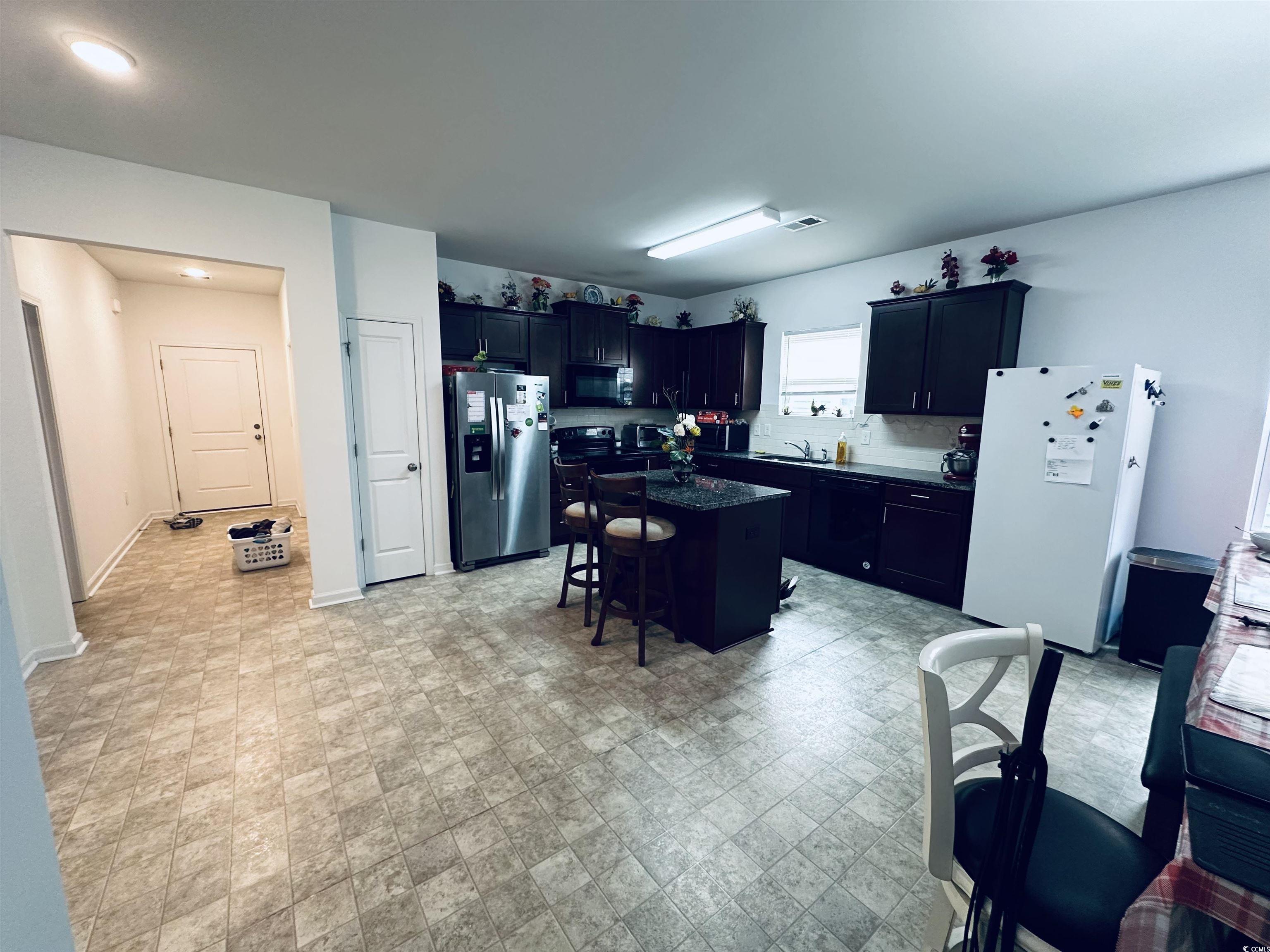 5260 Walnutwood Trail Myrtle Beach, SC 29579 - Photo 4 of 30 Kitchen with a kitchen breakfast bar, black appliances, a center island, dark cabinetry, and dark stone countertops