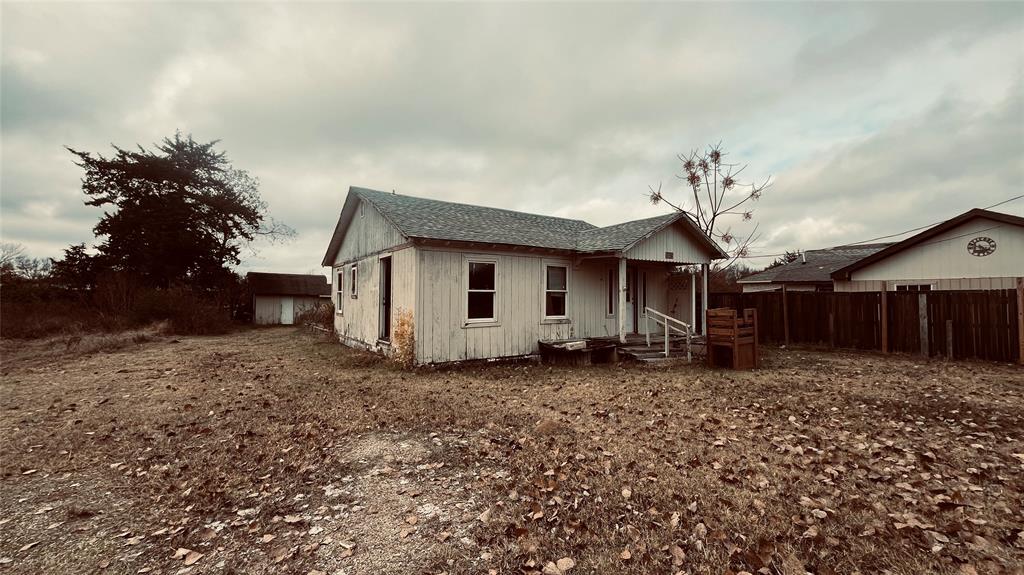 Front view of existing single-family structure with weathered exterior, boarded windows, and overgrown yard. Structure appears uninhabitable and unsafe for entry.