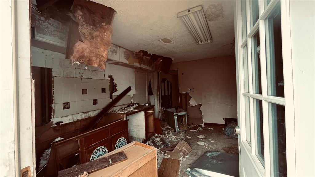1445 Elk Creek Road Dallas, TX 75253 - Photo 2 of 4 Interior shot showing extensive damage including collapsed ceiling, exposed insulation, and debris. Structure is not safe for access or occupancy.