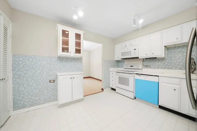 a kitchen with stainless steel appliances white cabinets and a refrigerator