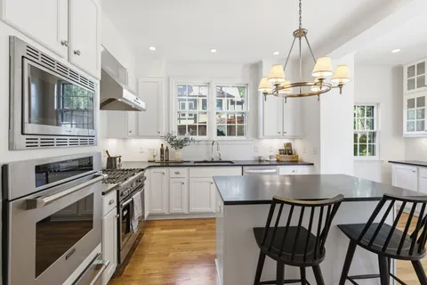 a kitchen with stainless steel appliances granite countertop a stove top oven a sink a dining table and chairs