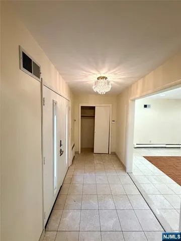 a view of empty room with wooden floor and kitchen