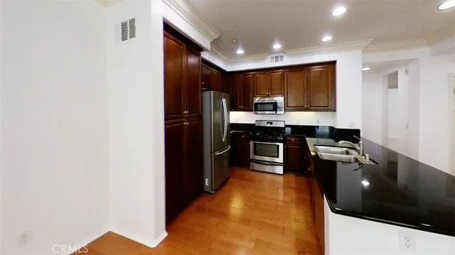 a kitchen with stainless steel appliances a sink a stove top oven a counter space and cabinets