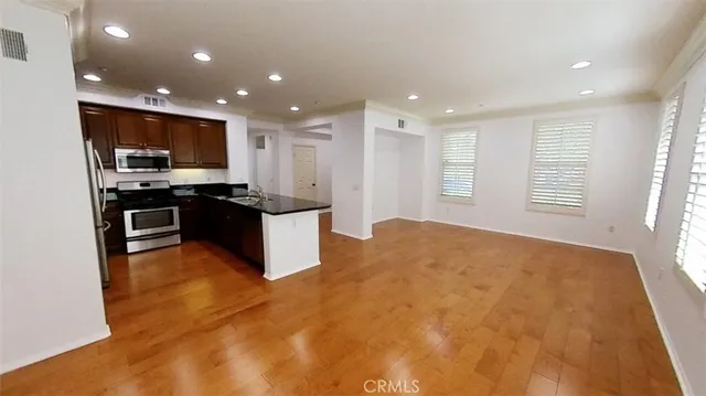 a kitchen with stainless steel appliances granite countertop a stove top oven a sink and a refrigerator