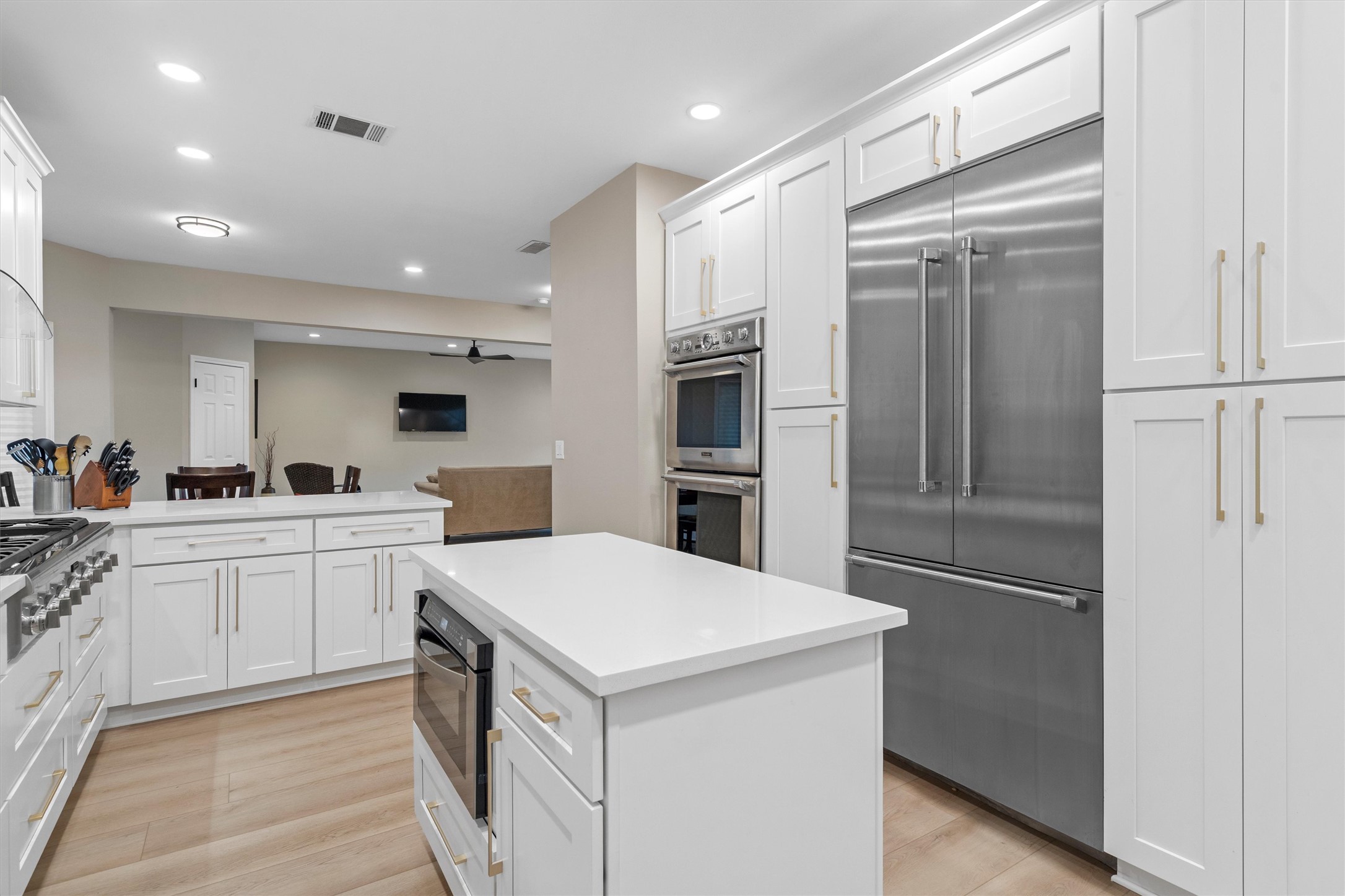 307 Hurst Creek Road Austin, TX 78734 - Photo 13 of 40 Modern kitchen featuring white shaker cabinetry, stainless steel appliances, a center island with built-in microwave, light wood-finish flooring, and recessed lighting