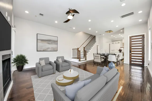 a living room with furniture kitchen view and a wooden floor