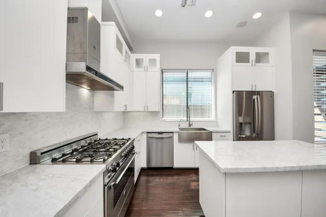 a large white kitchen with a large counter top appliances and cabinets