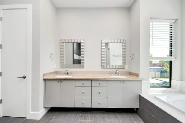 a spacious bathroom with a double vanity sink a large mirror and a bathtub