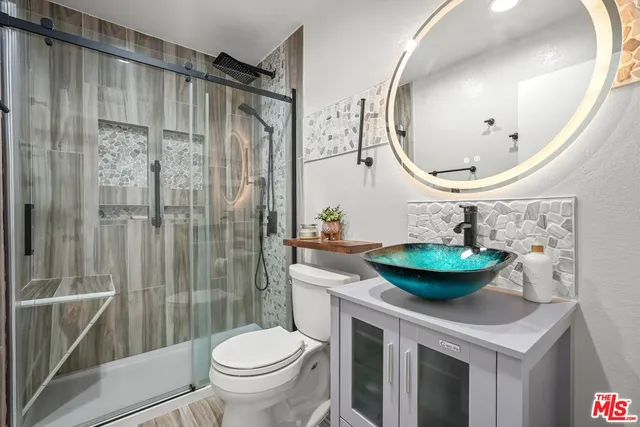 a bathroom with a granite countertop sink a toilet and a mirror