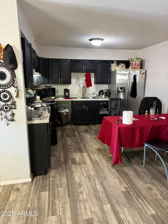 a kitchen with stainless steel appliances granite countertop a refrigerator a sink dishwasher a stove and a dining table with wooden floor