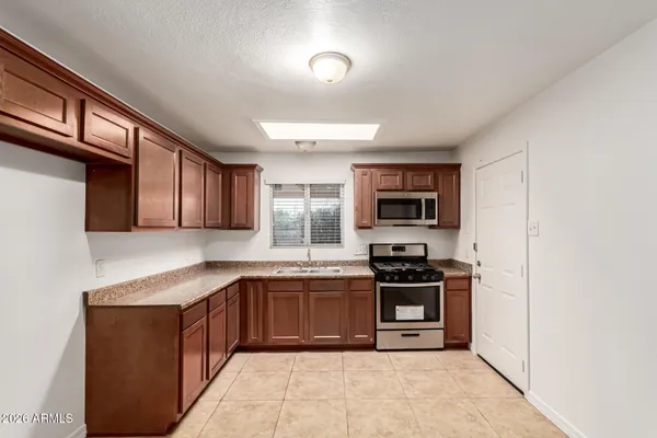 a kitchen with stainless steel appliances granite countertop a stove top oven a sink dishwasher and a refrigerator