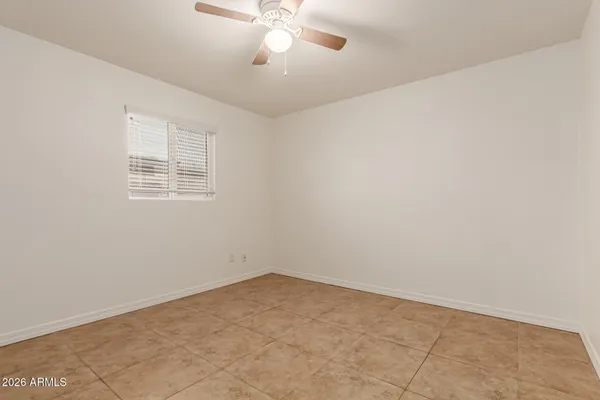 an empty room with a chandelier fan and windows