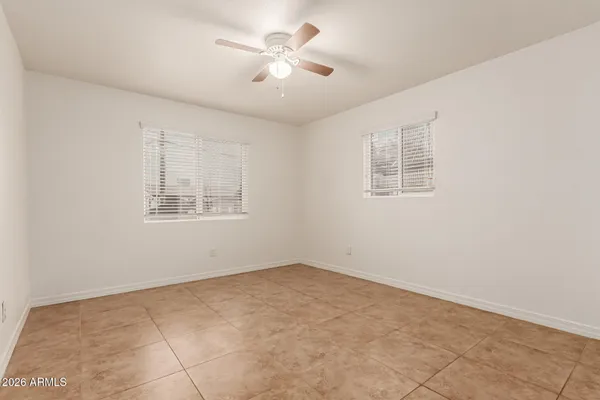 an empty room with windows and fan