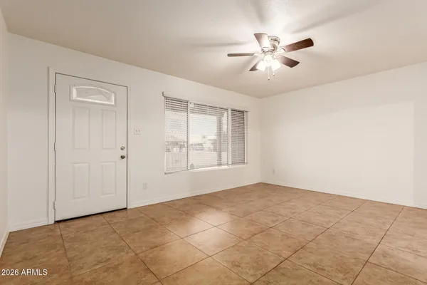 a view of an empty room with chandelier fan and fire place