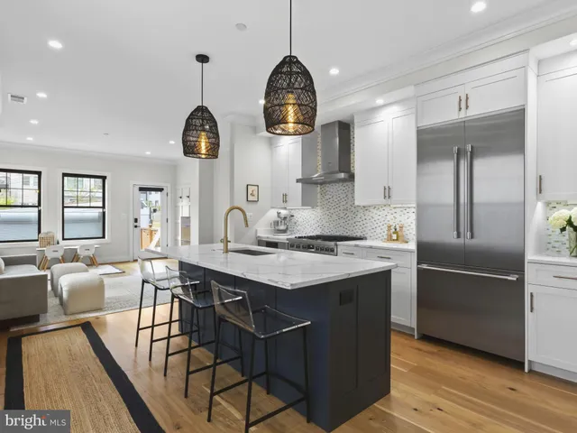 a kitchen with stainless steel appliances granite countertop a sink a stove and a dining table with wooden floor