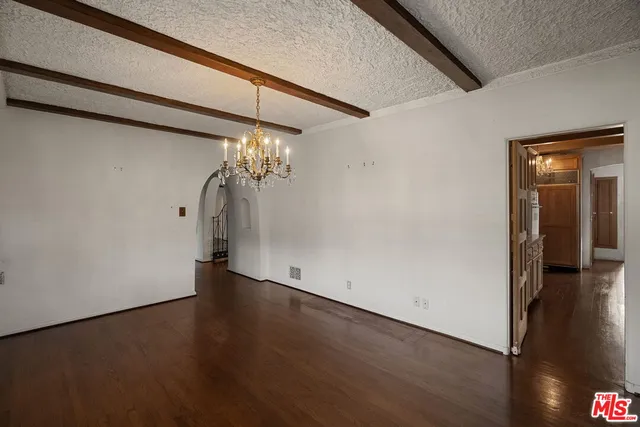 a view of a hallway with wooden floor and a chandelier