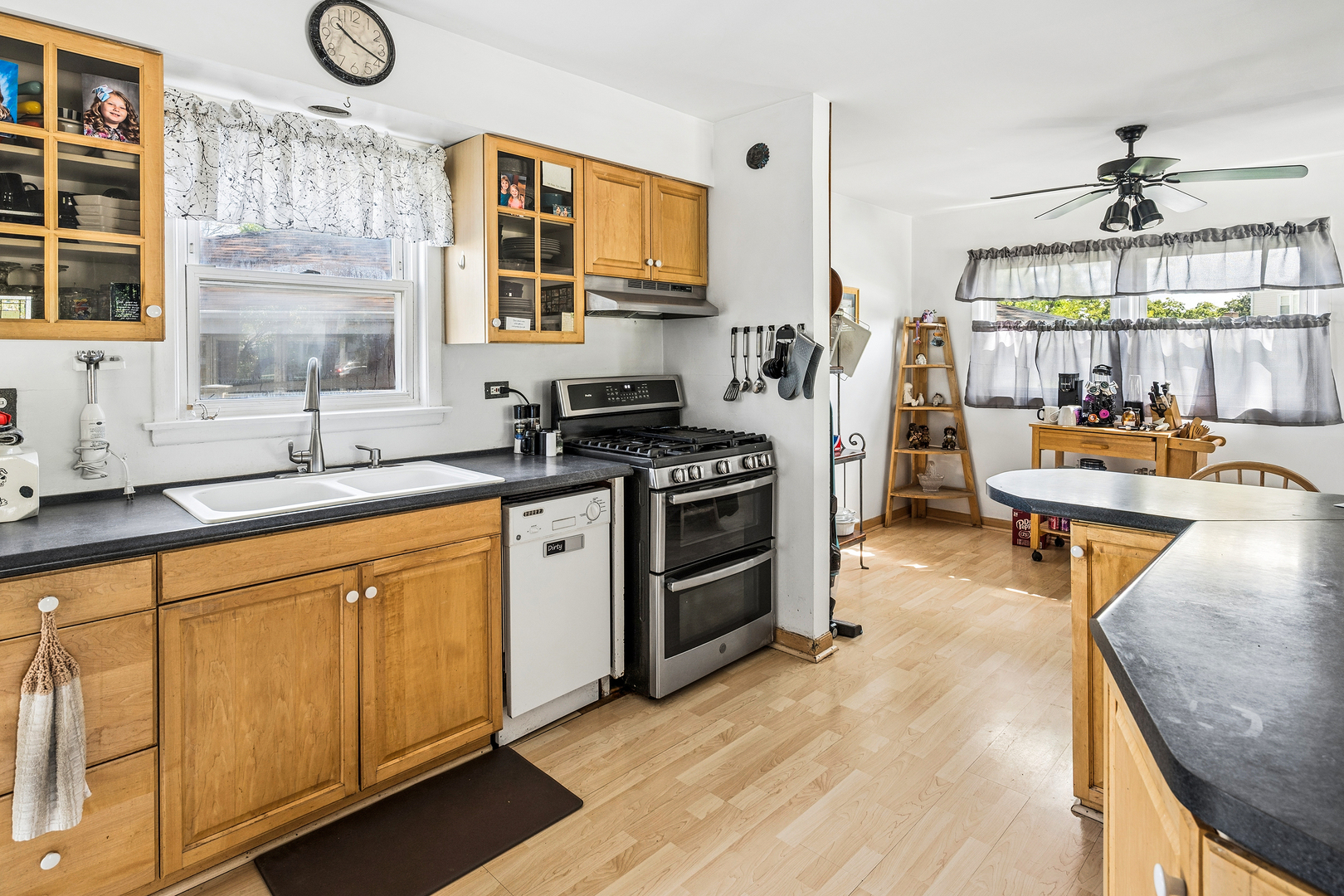 8330 Gross Point Road Morton Grove, IL 60053 - Photo 6 of 22 a kitchen with stainless steel appliances granite countertop a stove a sink dishwasher and white cabinets with wooden floor