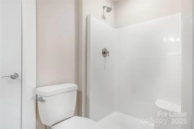 a white toilet sitting next to a shower