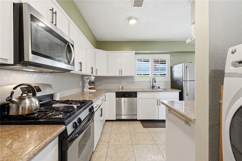 1237 South Clover Street Visalia, CA 93277 - Photo 12 of 30 a kitchen with stainless steel appliances granite countertop a sink and a stove top oven