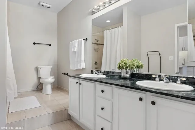 a bathroom with a granite countertop sink a toilet and a mirror