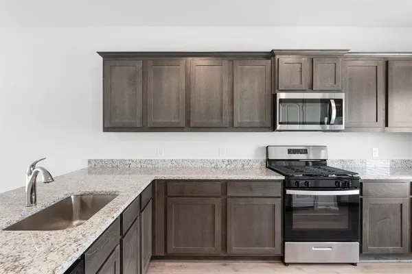 a kitchen with stainless steel appliances granite countertop a sink stove and microwave