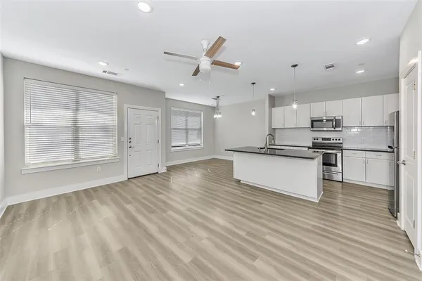 a kitchen with stainless steel appliances granite countertop a stove top oven a refrigerator and white cabinets with wooden floor