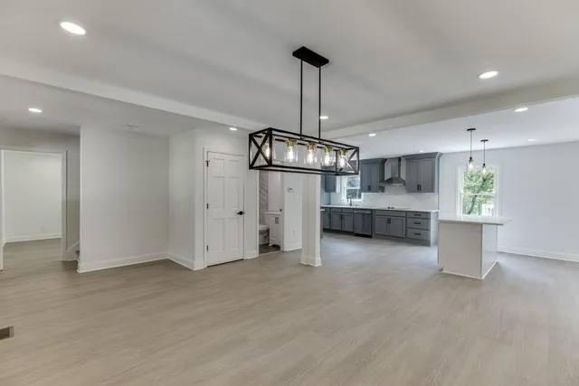 a kitchen with stainless steel appliances granite countertop a sink a stove a refrigerator and island with wooden floor