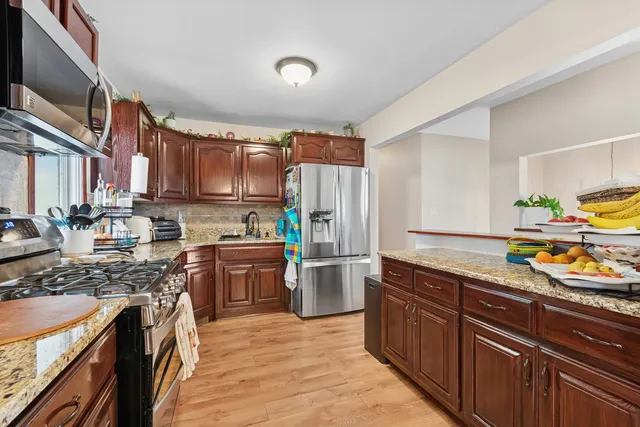 a kitchen with stainless steel appliances granite countertop a stove top oven a sink dishwasher and cabinets with wooden floor