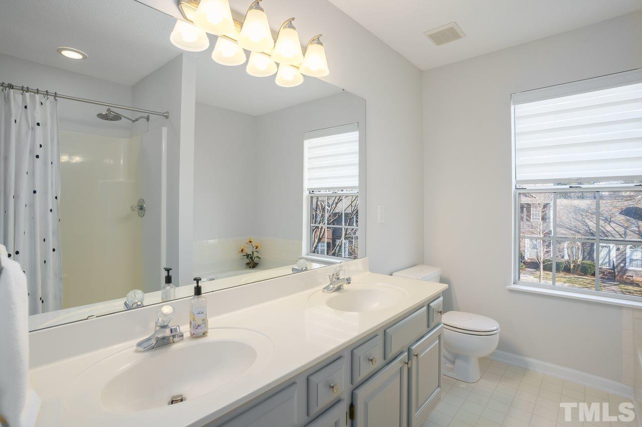 4469 Still Pines Drive Raleigh, NC 27613 - Photo 22 of 28 a bathroom with a granite countertop sink a toilet and a mirror